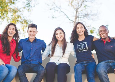 A group of young people sitting together smiling.