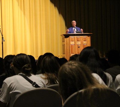 A person standing at a podium in front of a crowd of people.