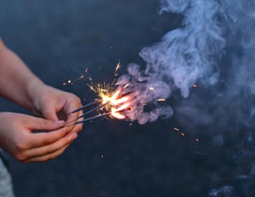 A hand holding a stick with fire.
