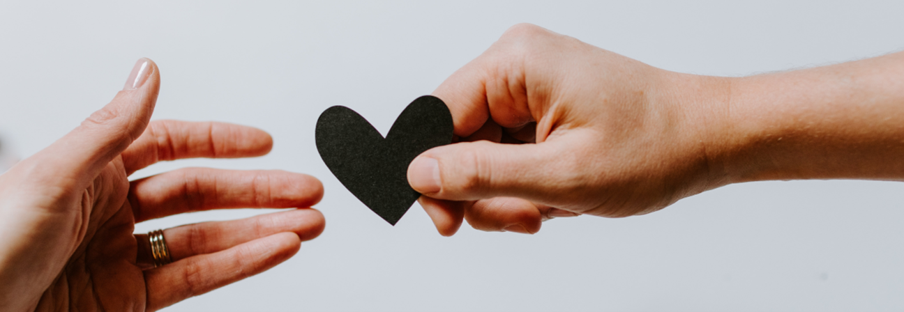 A pair of hands holding a black heart.