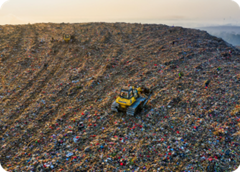 A truck driving through a large pile of trash.