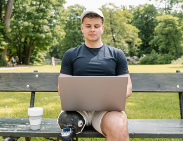 A person sitting on a bench with a laptop and a cup of coffee.