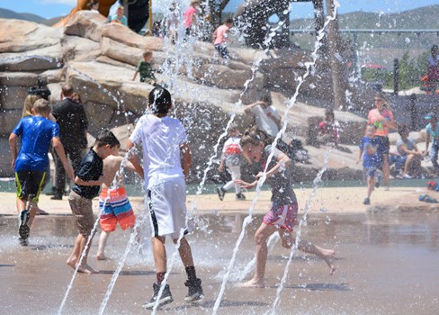 A group of people playing in a water fountain.
