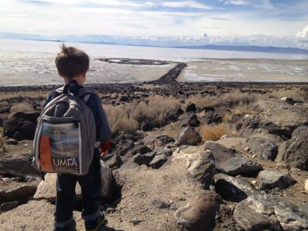 child takes in the spiral jetty with a umfa family backpack on his back