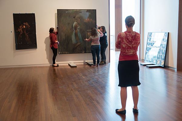 curator whitney tassie (foreground) and collections staff install british artist