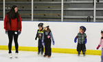 A person and a group of kids on an ice rink.
