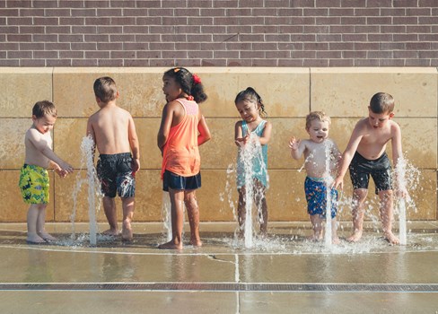 A group of children playing in a water fountain.