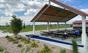 A covered patio with a picnic table and a large covered area.