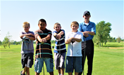 A group of boys posing for a picture on a golf course.